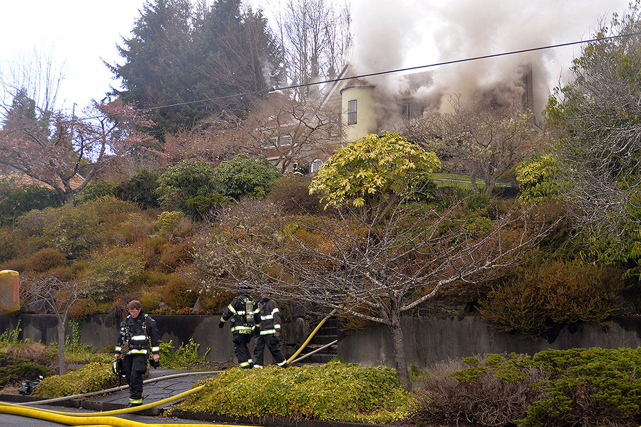 LOUIS KRAUSS | THE DAILY WORLD Firefighters walk away from a house fire on West 10th Street in Aberdeen. The occupants escaped the building without sustaining injuries.