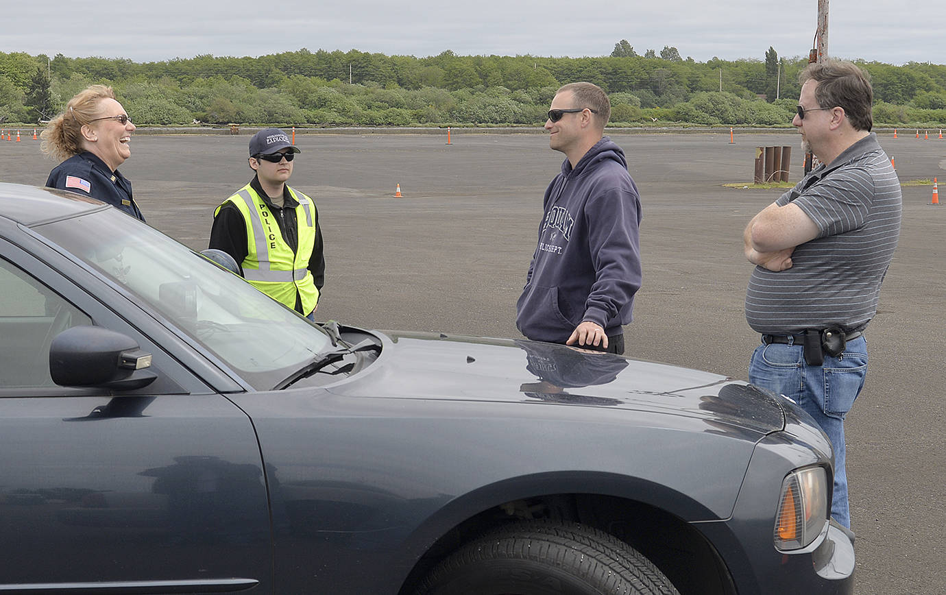 DAN HAMMOCK | THE DAILY WORLD                                Officers from several agencies take a break and cool their engines in between courses at a tactical driving course held at the old Bay City sorting yard in South Aberdeen May 24. From left are Elma Police chief Susan Schultz, an unidentified Police Explorer, instructor and Hoquiam officer David Peterson, and Ocean Shores Police Sgt. David McManus.