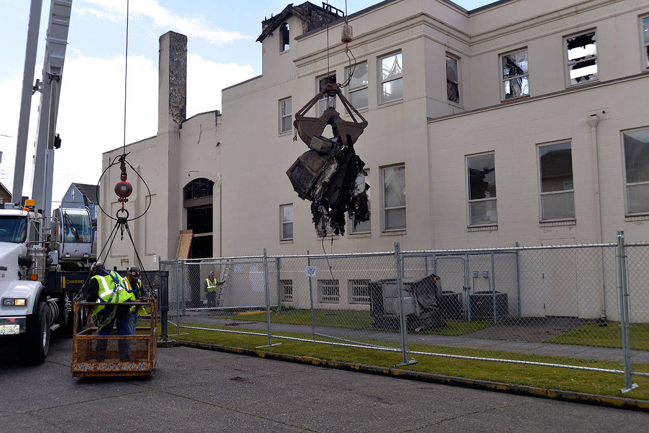 LOUIS KRAUSS | THE DAILY WORLD A crane removes a large air conditioner from the Aberdeen Armory Building on Wednesday. The city is working to remove all overhanging debris that could fall and harm those investigating the fire.