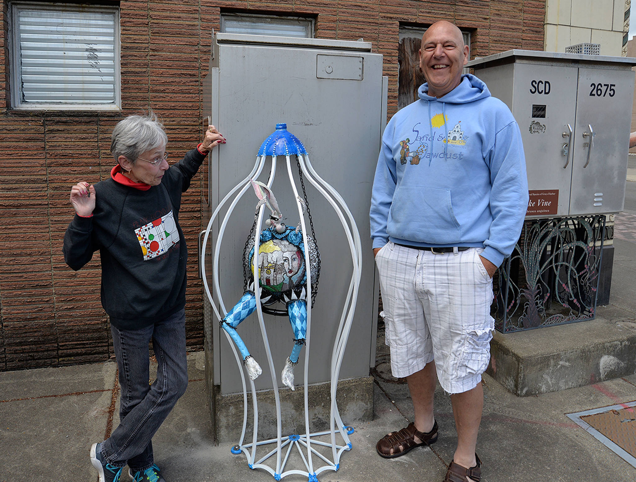 LOUIS KRAUSS | THE DAILY WORLD Sylvia Dickerson, left, and artist Doug Orr stand by the “Grizzly Hare” statue that was restored and reinstalled this week with three other critters.