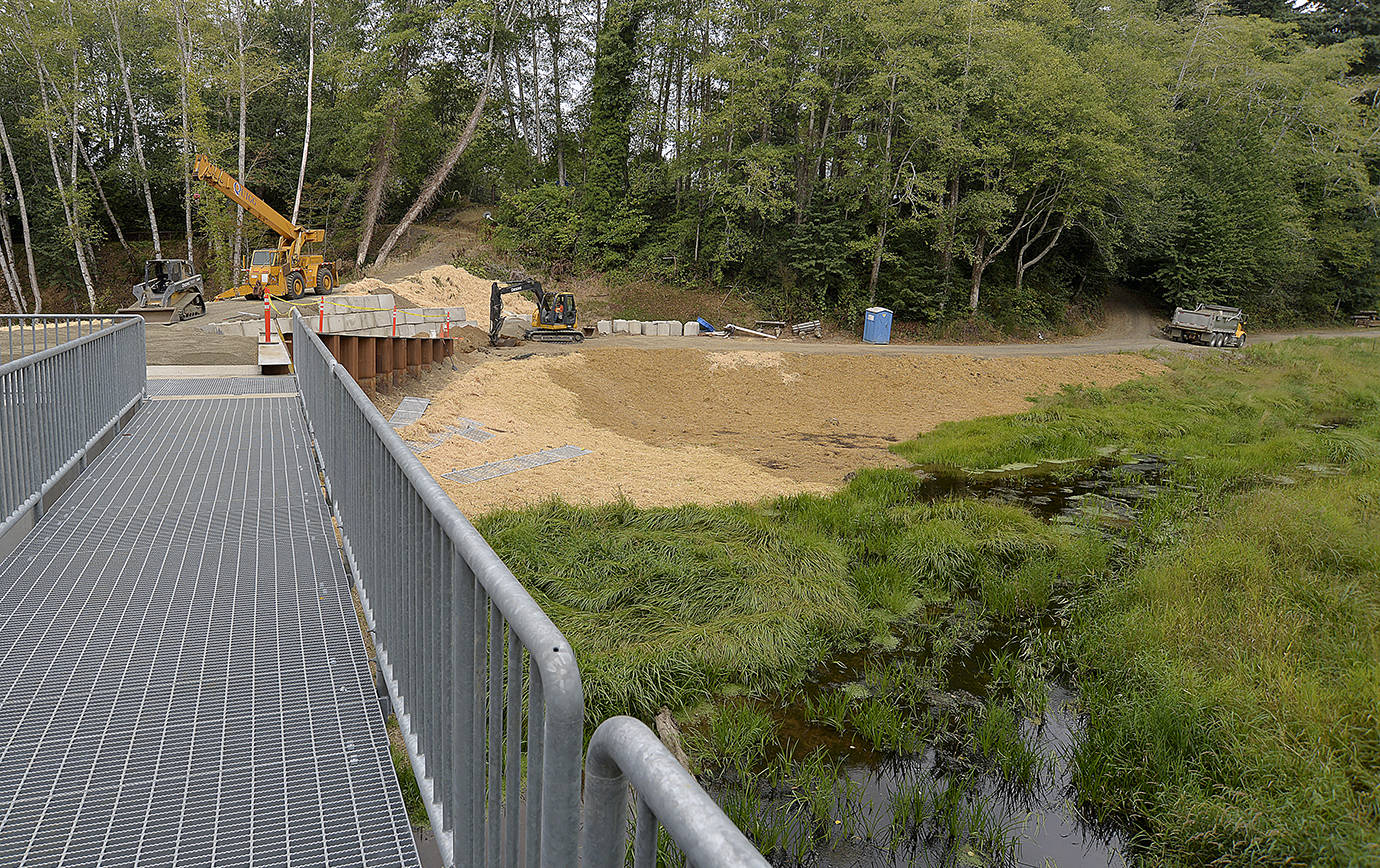 DAN HAMMOCK | THE DAILY WORLD                                Construction continues on the new Mill Creek Dam in Cosmopolis. City officials hope to dedicate the concrete, steel and earth structure on or around Sept. 22. The grassy area at right is where the pond used to be before a storm caused the old earthen dam to breach in 2008.