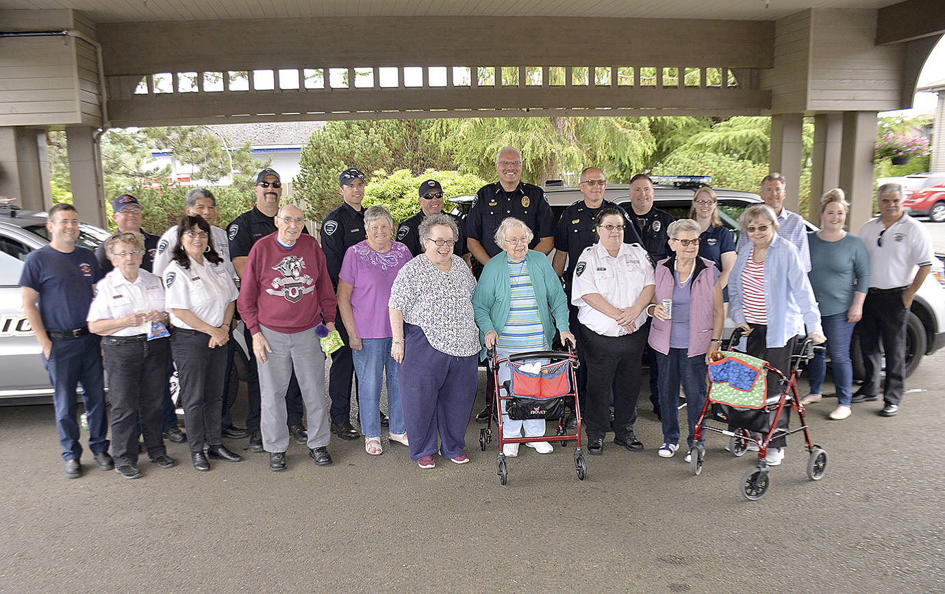 DAN HAMMOCK | GRAYS HARBOR NEWS GROUP                                First stop for the Hoquiam police and fire departments was Channel Point Village during Tuesday’s National Night Out celebration. Here firefighters, police and city officials pose for a picture with a few of the retirement community’s residents.