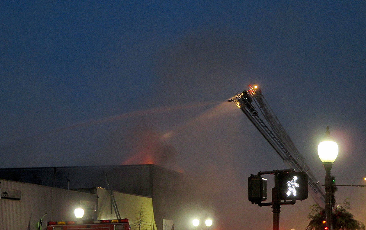 COURTESY DANIEL HOEFS                                Flames are visible from the roof of a building at 115 W. Heron St. early Saturday morning. The early morning fire gutted the building, which formerly housed C&C Motor Sports on the ground floor and the Revival Grays Harbor on the second.