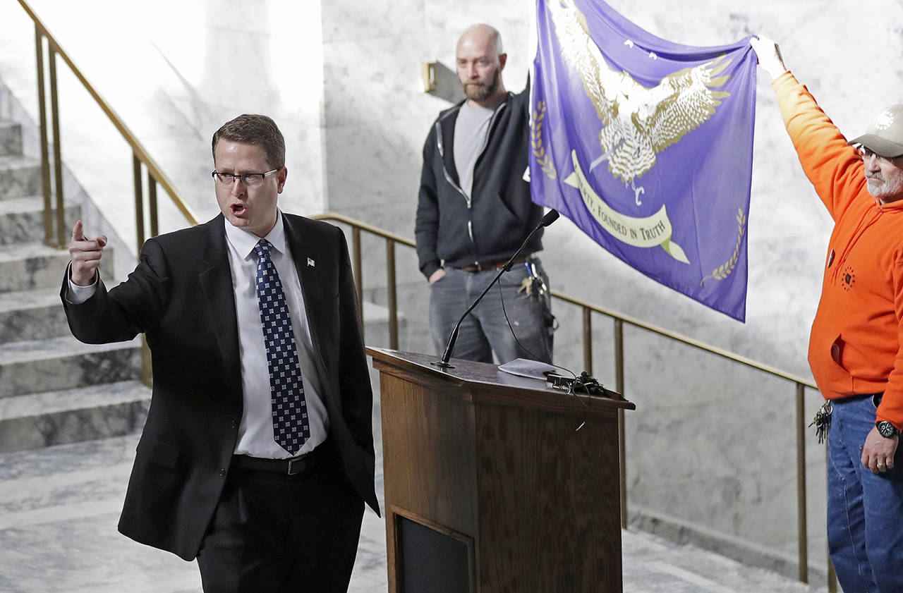 Rep. Matt Shea (left) gestures as he gives a speech in front of the liberty state flag Feb. 15, 2019, at the Capitol in Olympia. (AP Photo/Ted S. Warren)