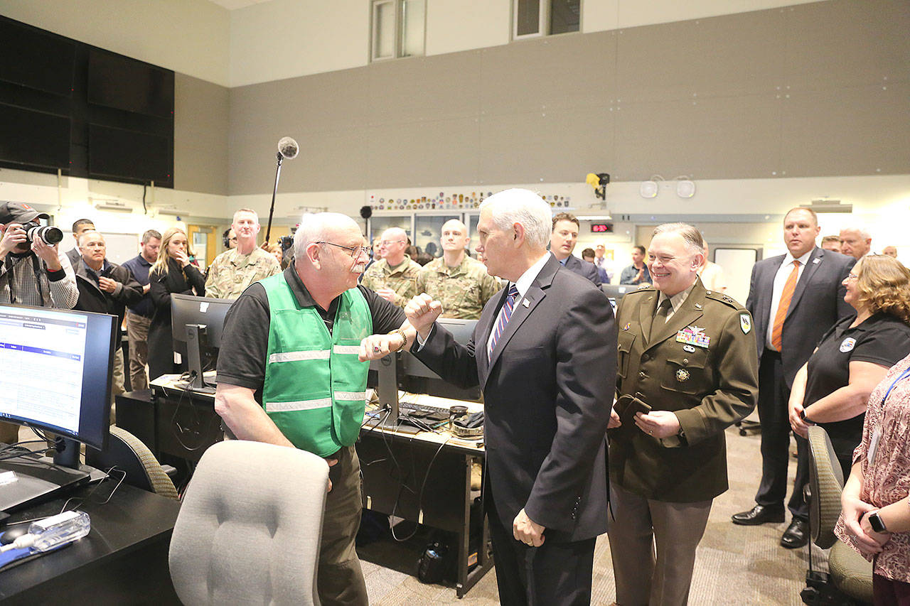 Photo by Steven Friederich                                 Vice President Mike Pence, center, exchanges a “bump” with Andy Leneweaver, operations manager of the Washington state Emergency Operations Center, at Camp Murray on Thursday afternoon.                                Vice President Mike Pence exchanges an elbow bump with Andy Leneweaver, operations manager the Washington state Emergency Operations Center at Camp Murray on Thursday afternoon. (Photo by Steven Friederich)