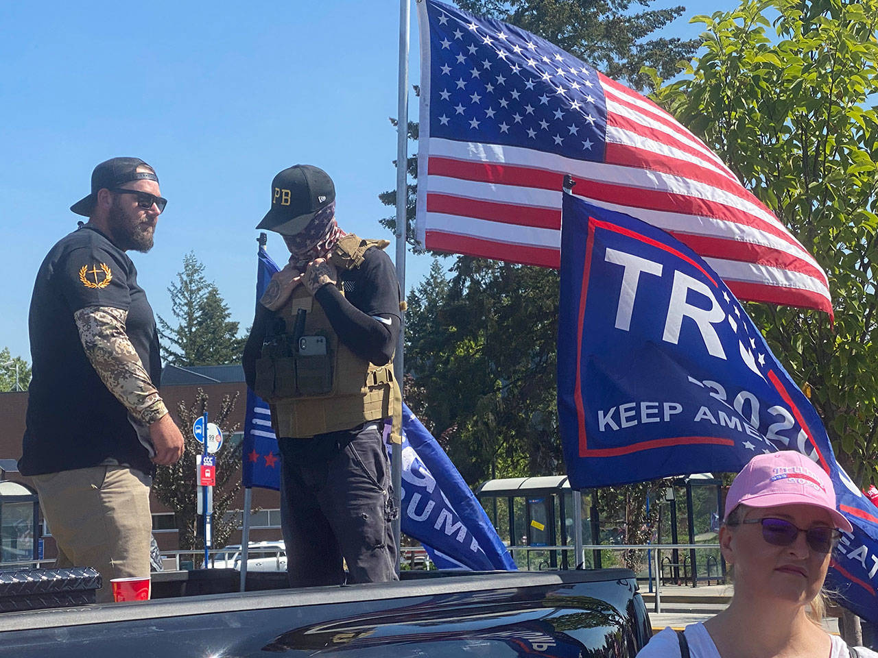 Men wearing symbols of Proud Boys, an alleged right-wing extremist group, stand watch as supporters of President Trump kick off a truck caravan near Portland on Monday. (Richard Read/Los Angeles Times)