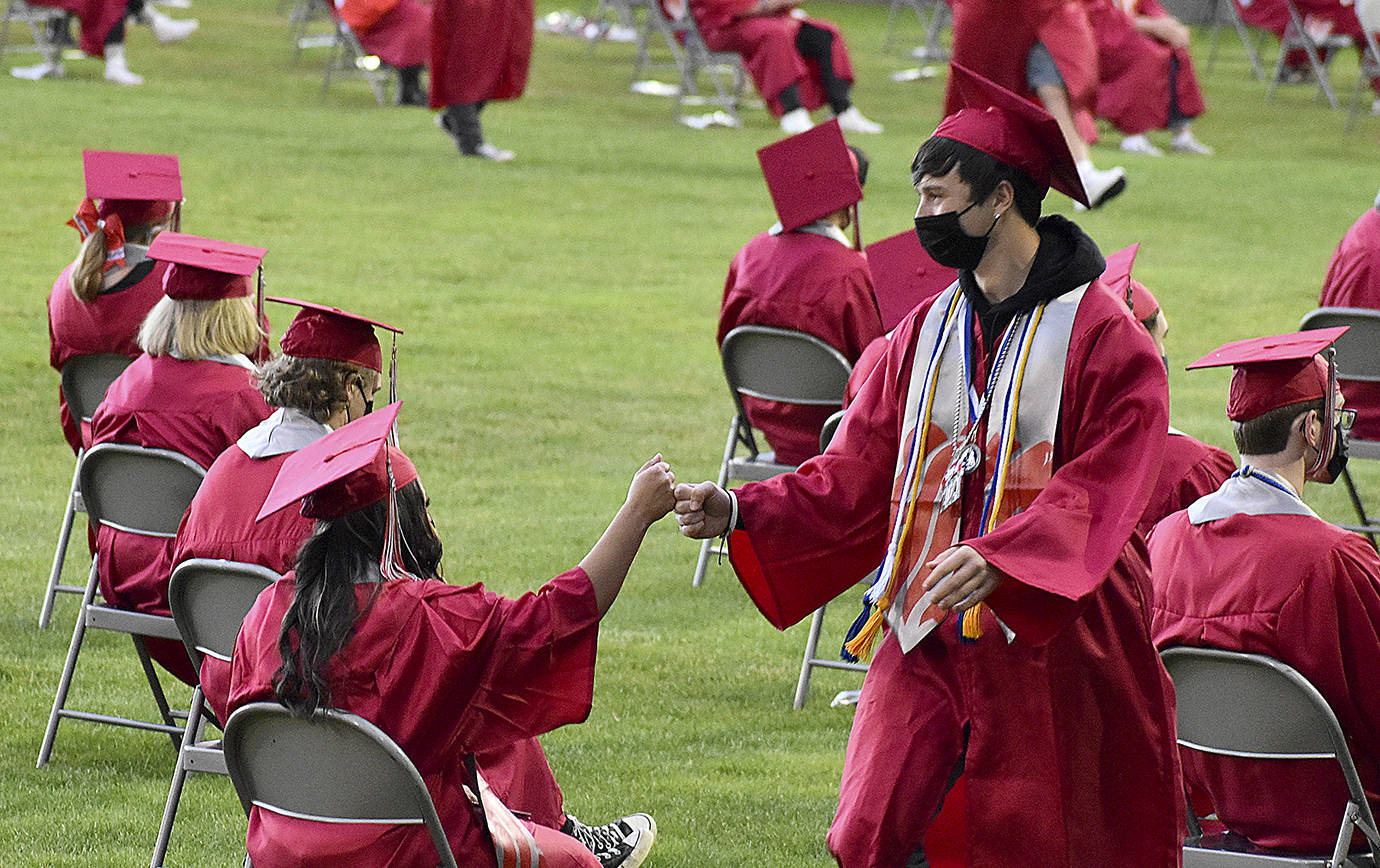 DAN HAMMOCK | THE DAILY WORLD 
Students exchange a fist bump as one waits for her name to be called and the other returns to his seat with his diploma.