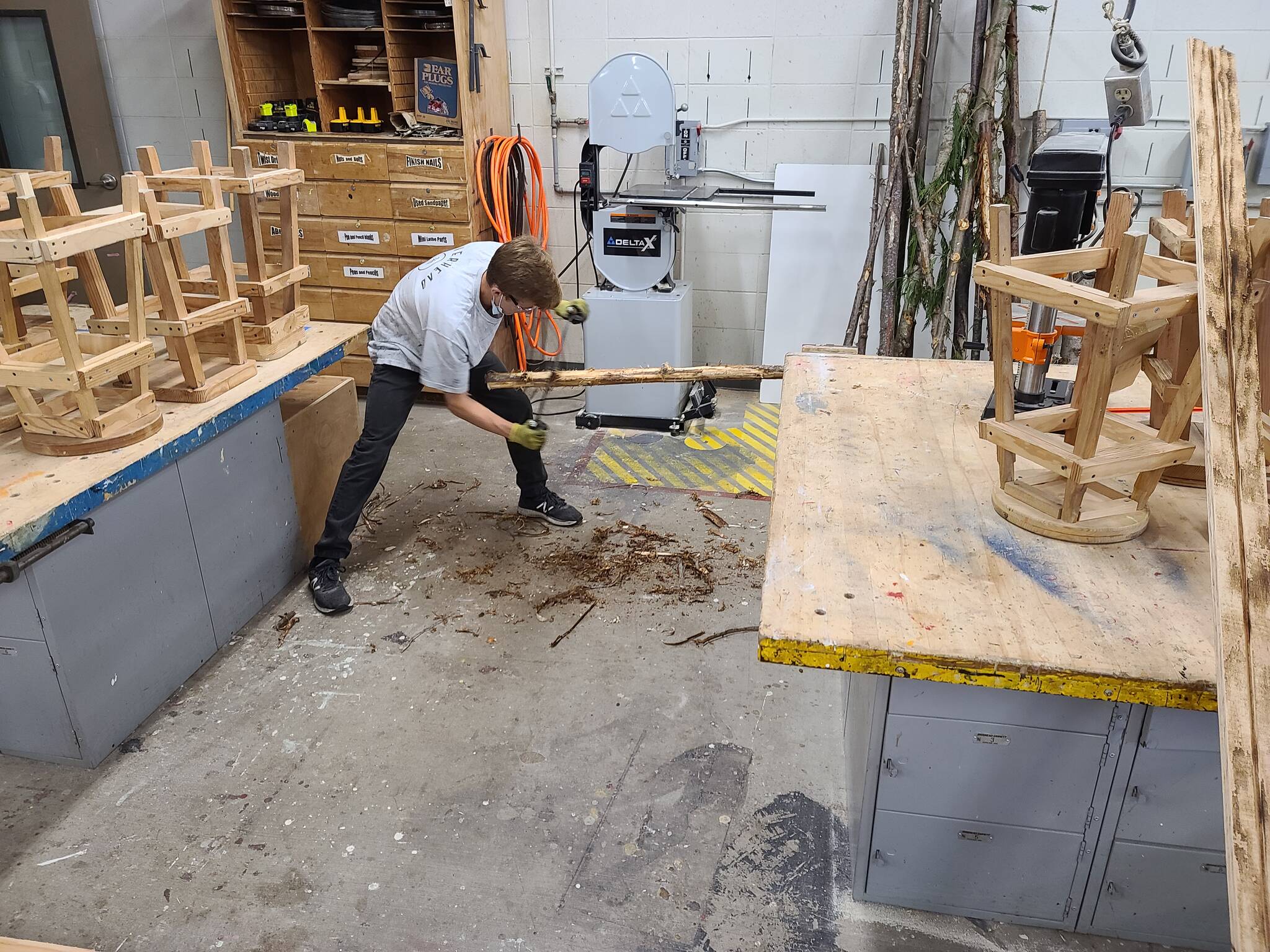 Ocosta Junior-Senior High School student Dylan Todd works to remove bark during his group’s project to build an event safety trailer that helps store and provide various materials to help residents fight COVID-19 during community events. (Provided photo)