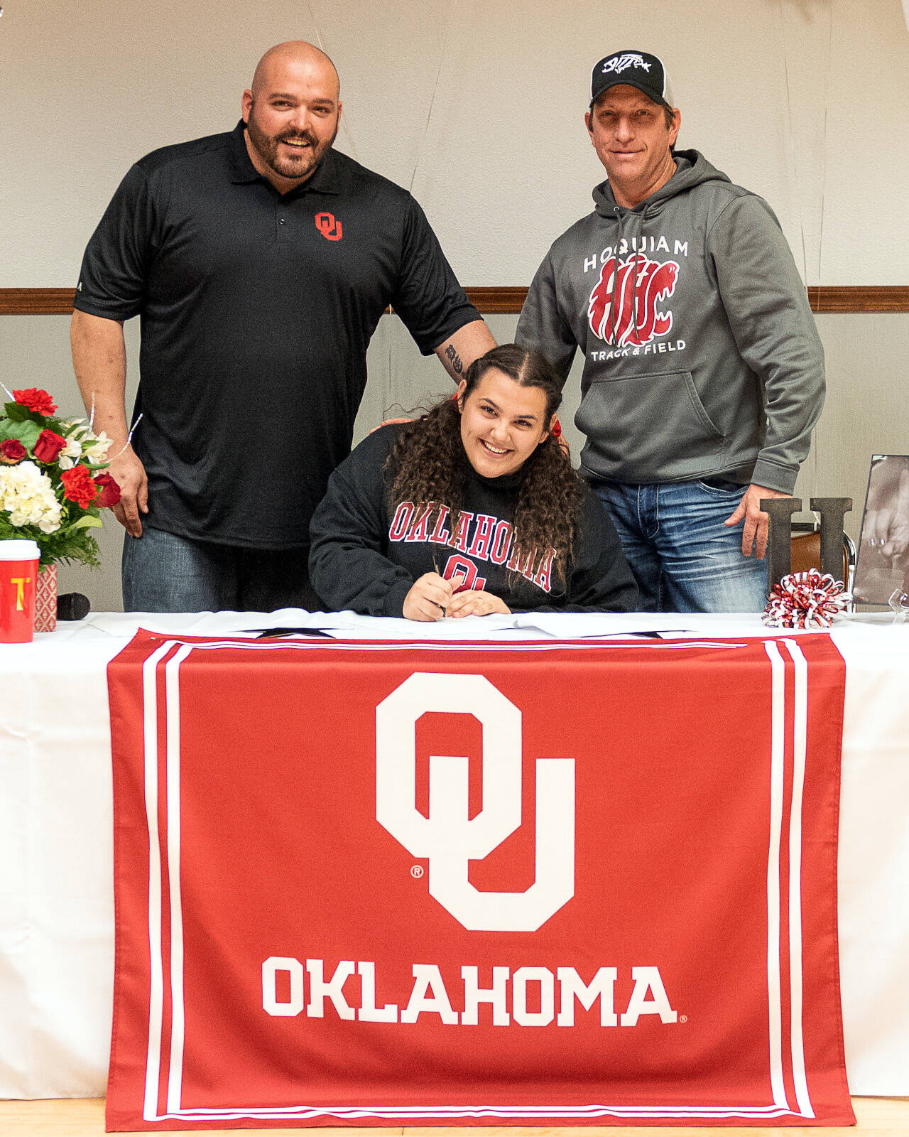 PHOTO BY PAMELA PELAN Hoquiam track and field athlete Tyara Straka, sitting, is flanked by her father, Shaun, left, and Hoquiam head coach Tim Pelan during a signing ceremony on Saturday.