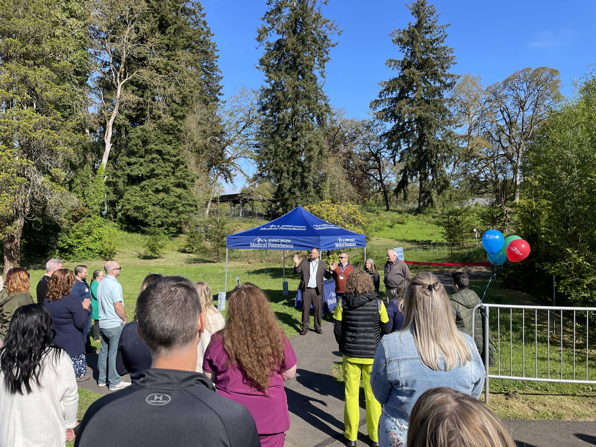 Photo Courtesy of Nichole Pas 
Local community members, Summit Pacific Medical Center staff, and the Medical Foundation Board gather around Summit Pacific CEO Josh Martin to celebrate the grand opening of the trail. This is the third trail to be completed on the hospital campus grounds and is open for all to enjoy.