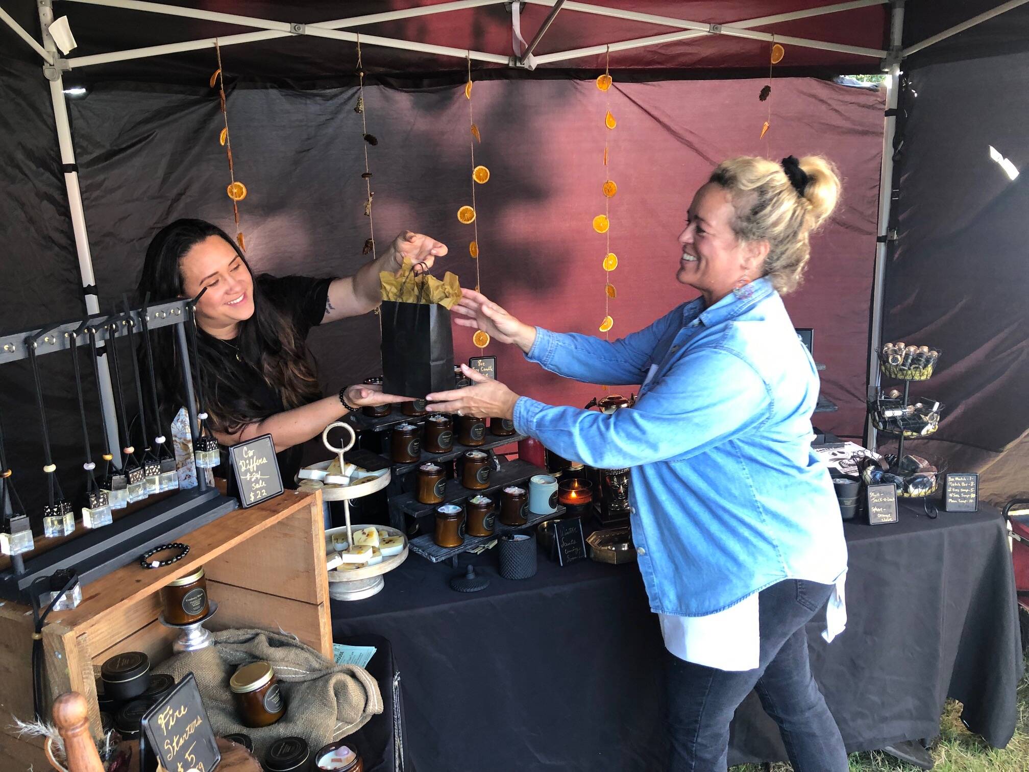 Amee Weasa of Tokeland Candle Works, left, sells some candles to Donya Haas, a vendor selling Pussycat Cupcakes on Sunday at Grayland’s Cranberry Fest.