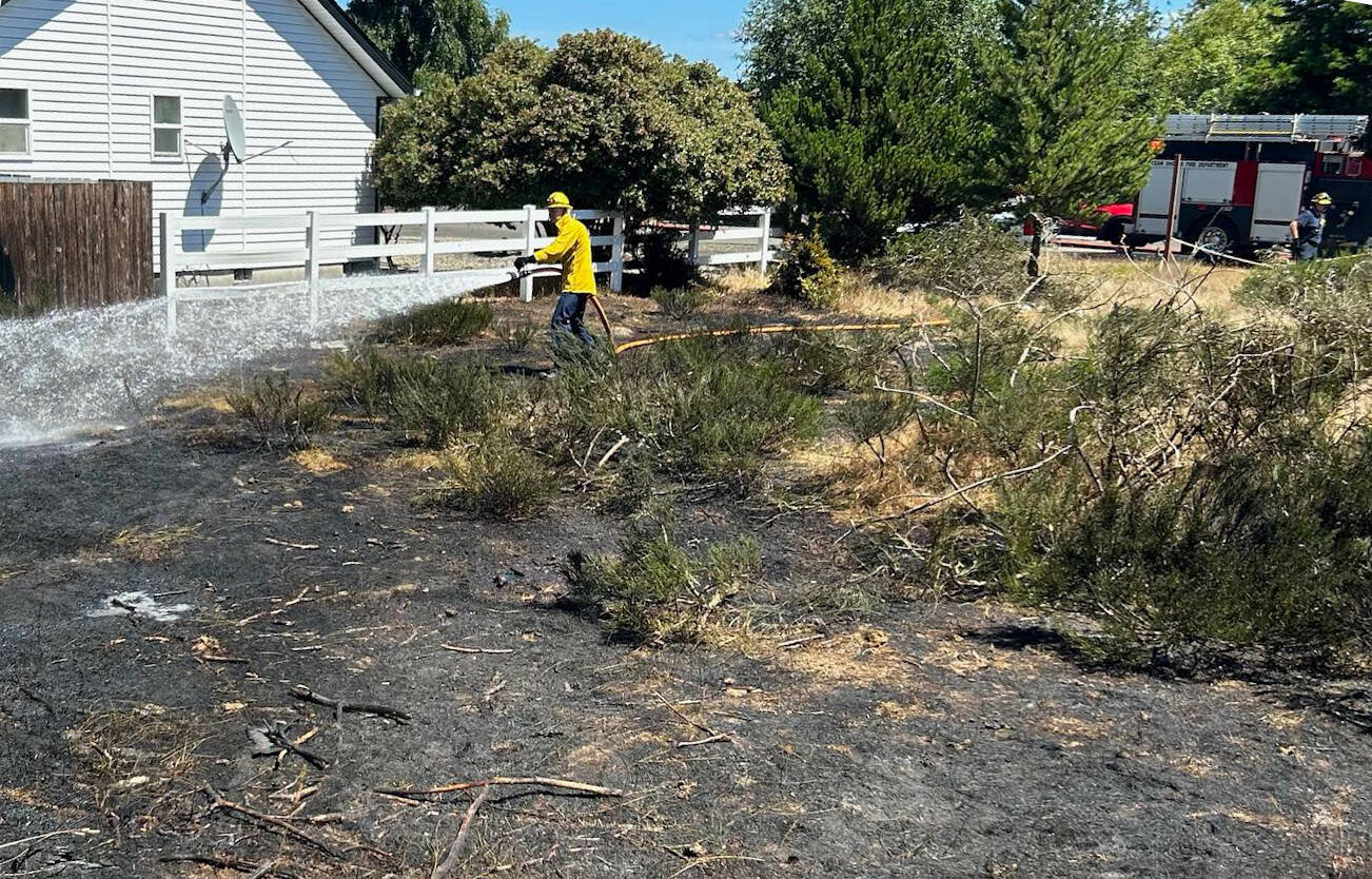 Firefighter/EMT Nick Frymire of the Ocean Shores Fire Department sprays down a burned area caused by a grass fire on July 18. (Michael S. Lockett / The Daily World)