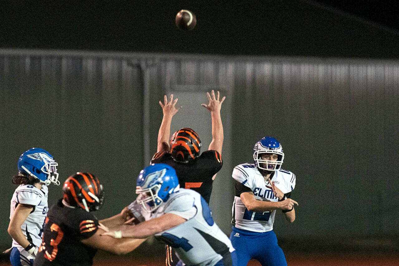 DYLAN WILHELM | THE CHRONICLE Elma QB Carter Studer, right, tosses a pass above the leaping arms of Centralia defensive lineman Jorge Leal during the Eagles’ 21-14 overtime victory on Friday in Centralia.