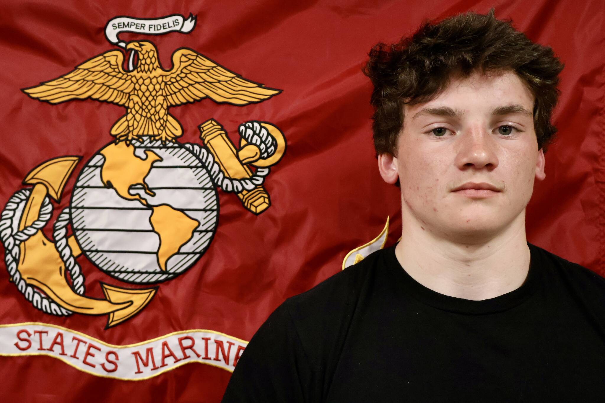 Dominik Jerome, left, stands before the Marine Corps flag during a send off before he departs for Marine Corps basic training. (Michael S. Lockett / The Daily World)