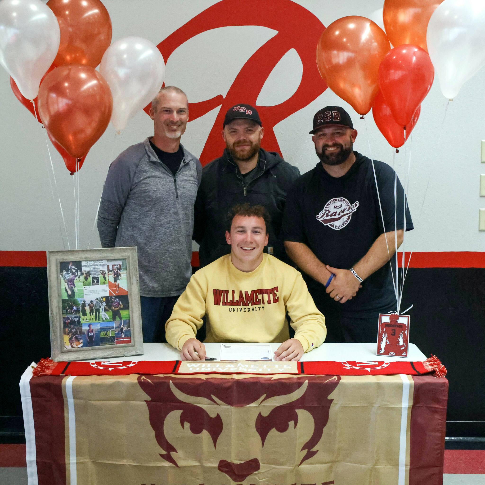 PHOTO BY LARRY BALE Raymond senior Austin Snodgrass (sitting) signed a Letter of Intent to compete in both football and track and field at Willamette University in the fall. Pictured with Snodgrass is (from left) Raymond athletic director Mike Tully and coaches Ken Minks and Luke Abbott.