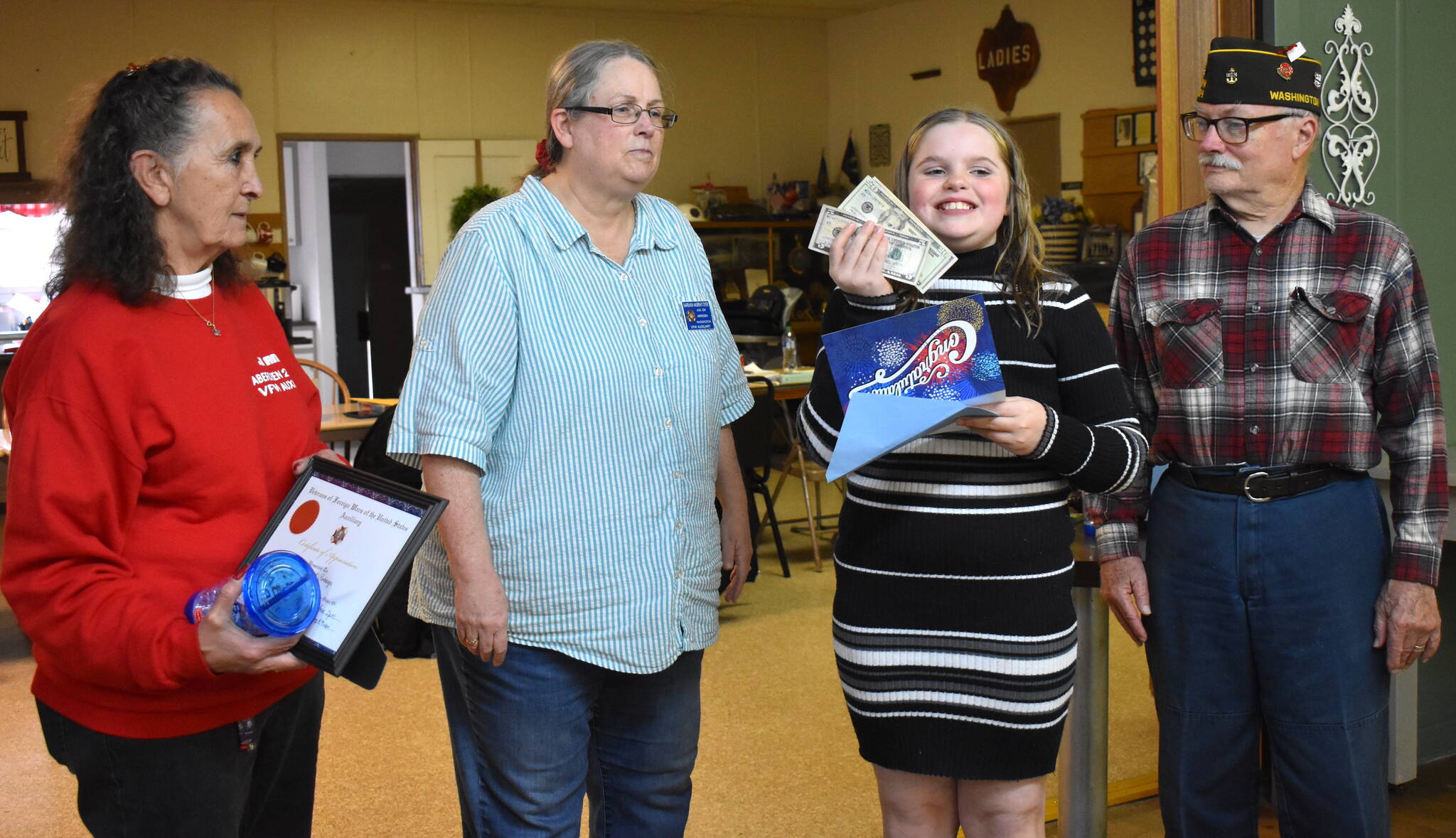 Matthew N. Wells / The Daily World
Pearl Robarge, second from right, glows after receiving her award of $75 in cash and a wood plaque from the VFW. Robarge, a fourth grader from McDermoth Elementary School, placed third in the VFW Red, White and Blue Scholarship Contest. The contest had nine singers — from kindergarten to 12th grade — from throughout Grays Harbor compete in singing “The Star Spangled Banner.” Jo Ann Briones Wadsworth, treasurer for VFW Post 224, far left, Barbara Dyer, president for VFW Post 224, left, and Anthony Magri, VFW 224’s post commander, helped present Pearl with her award on Tuesday night at American Legion Hall Post 5.