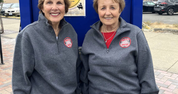 Bette Worth, left, and Bobbi McCracken are excited to bring everyone out to Aberdeen Summerfest on Saturday. The festival itself — stretching along the Broadway Street blocks between Market and Heron streets, goes from 10 a.m., but there is the Show and Shine Car Show that starts at 9:30 a.m. The duo, the rest of the Downtown Aberdeen Association, as well as the sponsors, work hard for this to succeed. Information can be found on all social media channels, local media, and flyers around town such as the one behind them. (Matthew N. Wells / The Daily World)