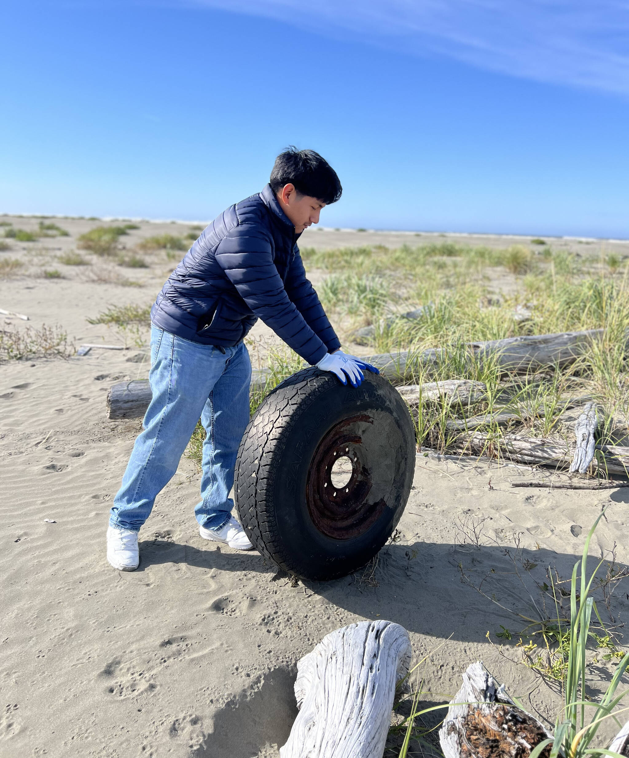 Faith Taylor-Eldred / Aberdeen School District
A student rolls a discarded tire off the beach.