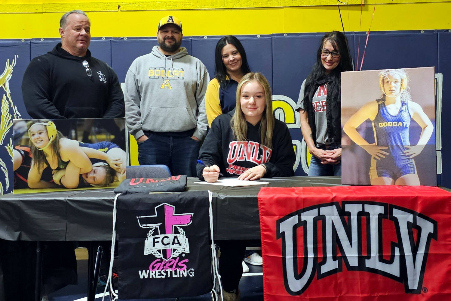 SUBMITTED PHOTO Aberdeen senior Felicia Bell (sitting) signed a National Letter of Intent to wrestle for the University of Nevada, Las Vegas at a ceremony at Aberdeen High School on Friday. Bell placed third in the state meet last season and currently has 100 wins in her prep career, the most of any Bobcat female wrestler in school history. Pictured behind Bell are (from left) father Don Bell, coaches Craig and Tamar Yakovich, and mother Michele Bell.